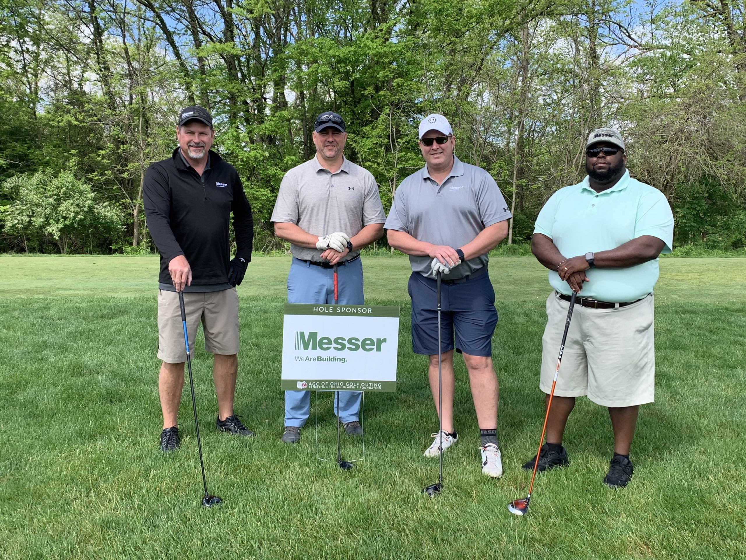 Messer Construction Company employees on the golf course in front of Messer sponsor signage