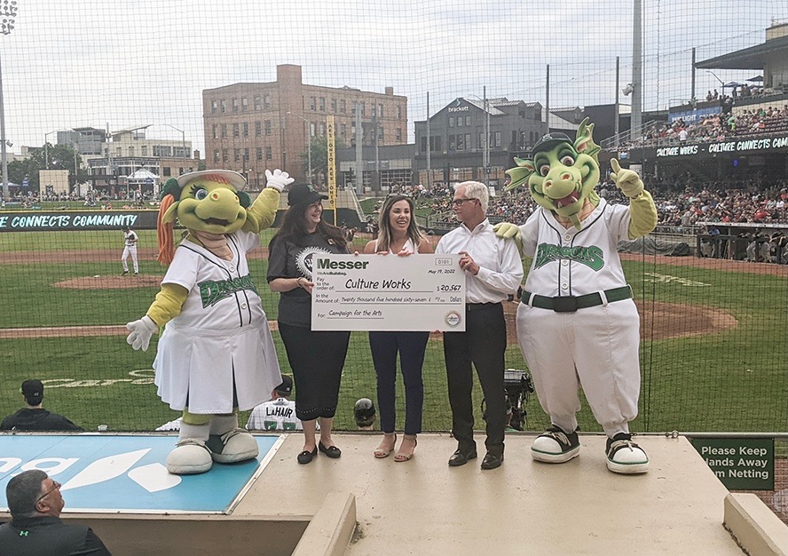 Messer Construction Company employee presenting large check at baseball game with mascots