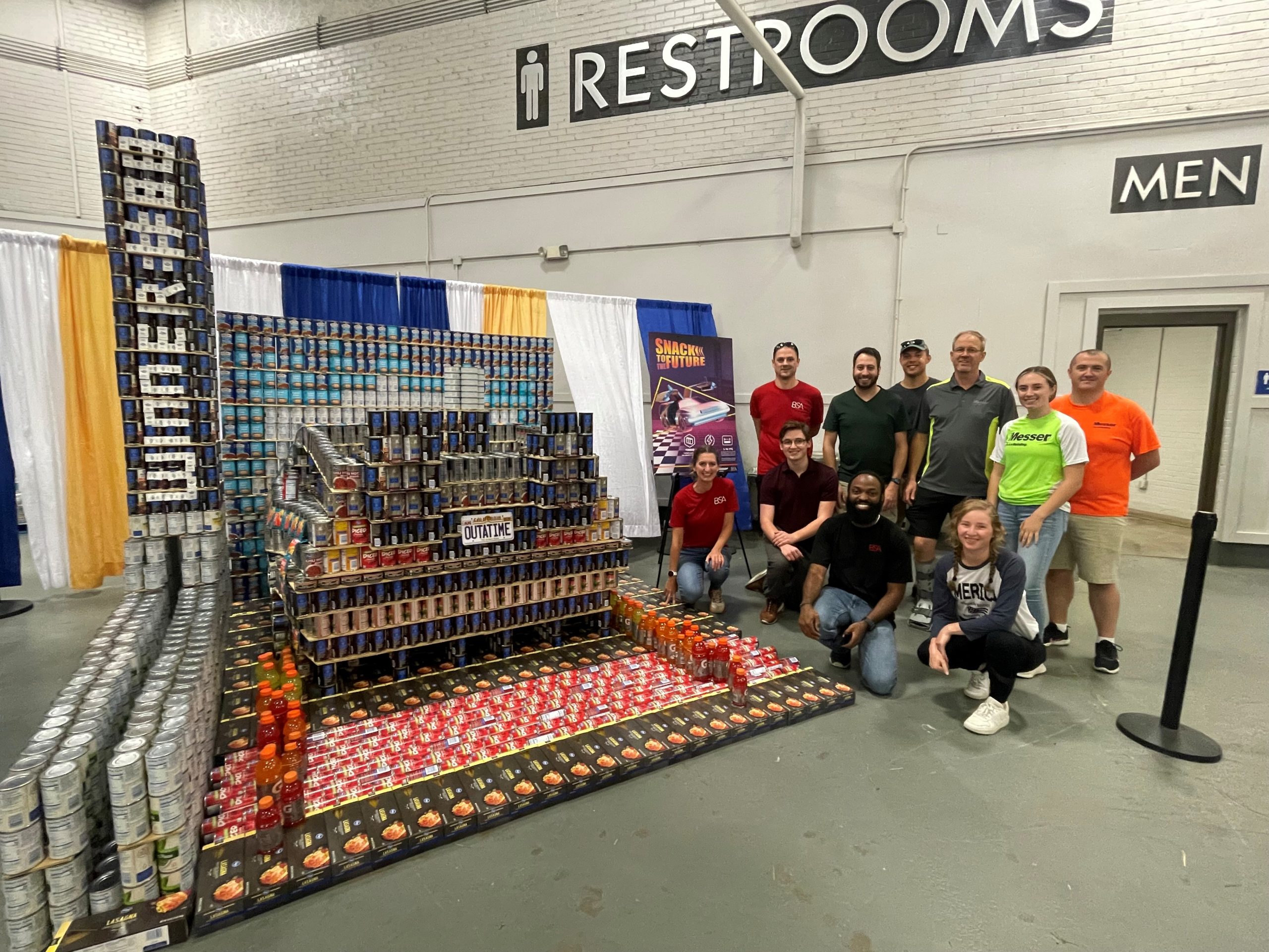 Messer Construction Co employees posing in front of a structure made out of canned goods