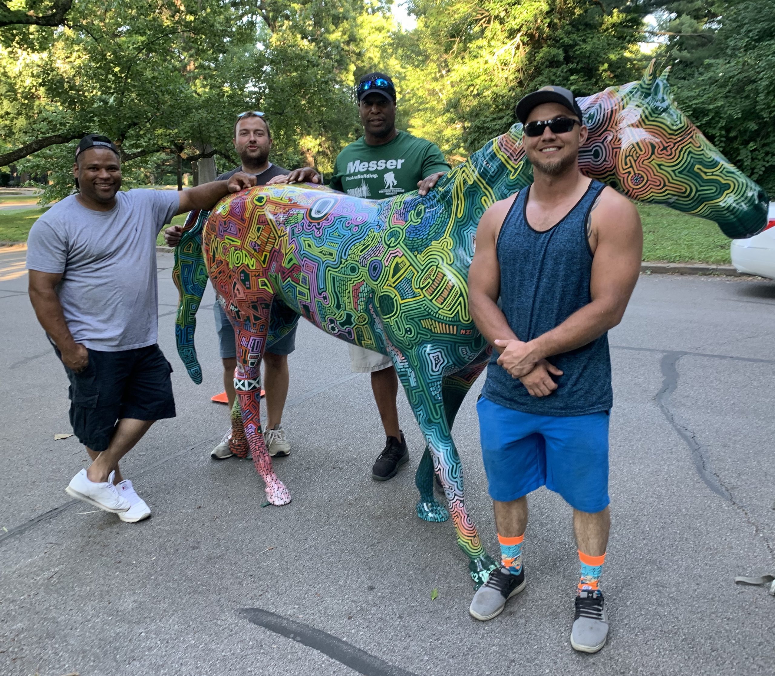 People standing with painted rainbow horse statute