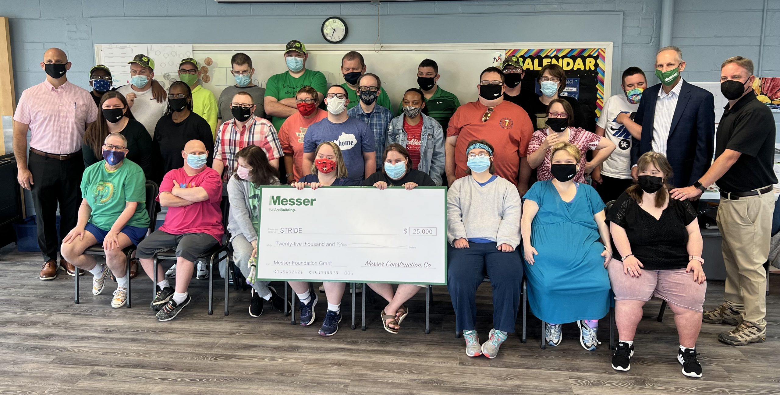 Group of people smiling holding a large check
