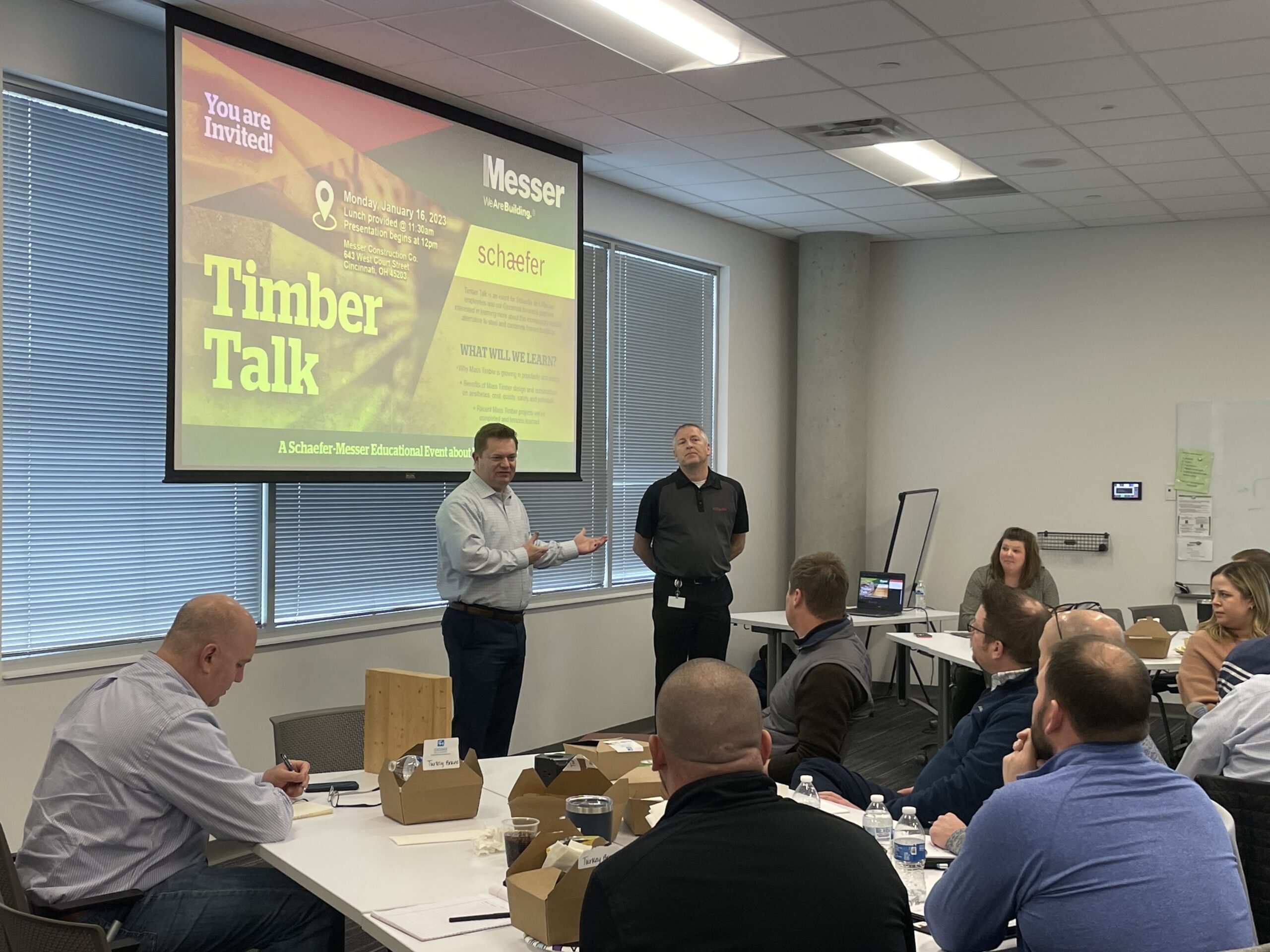 Two people presenting in a room full of people