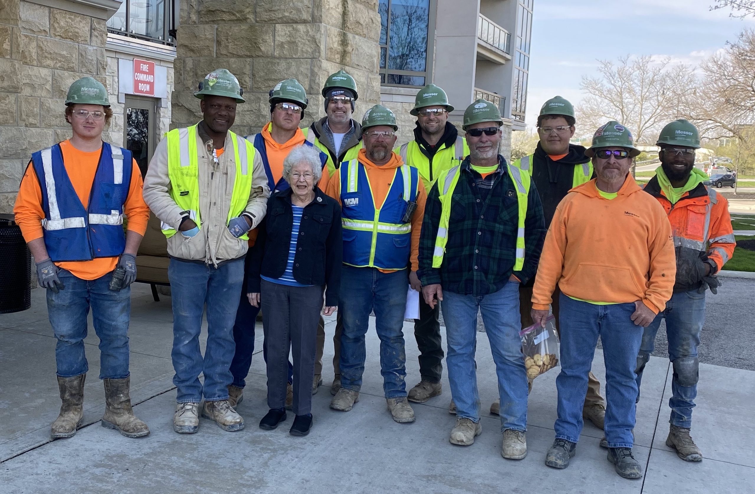 Construction workers standing outside posing for picture with resident