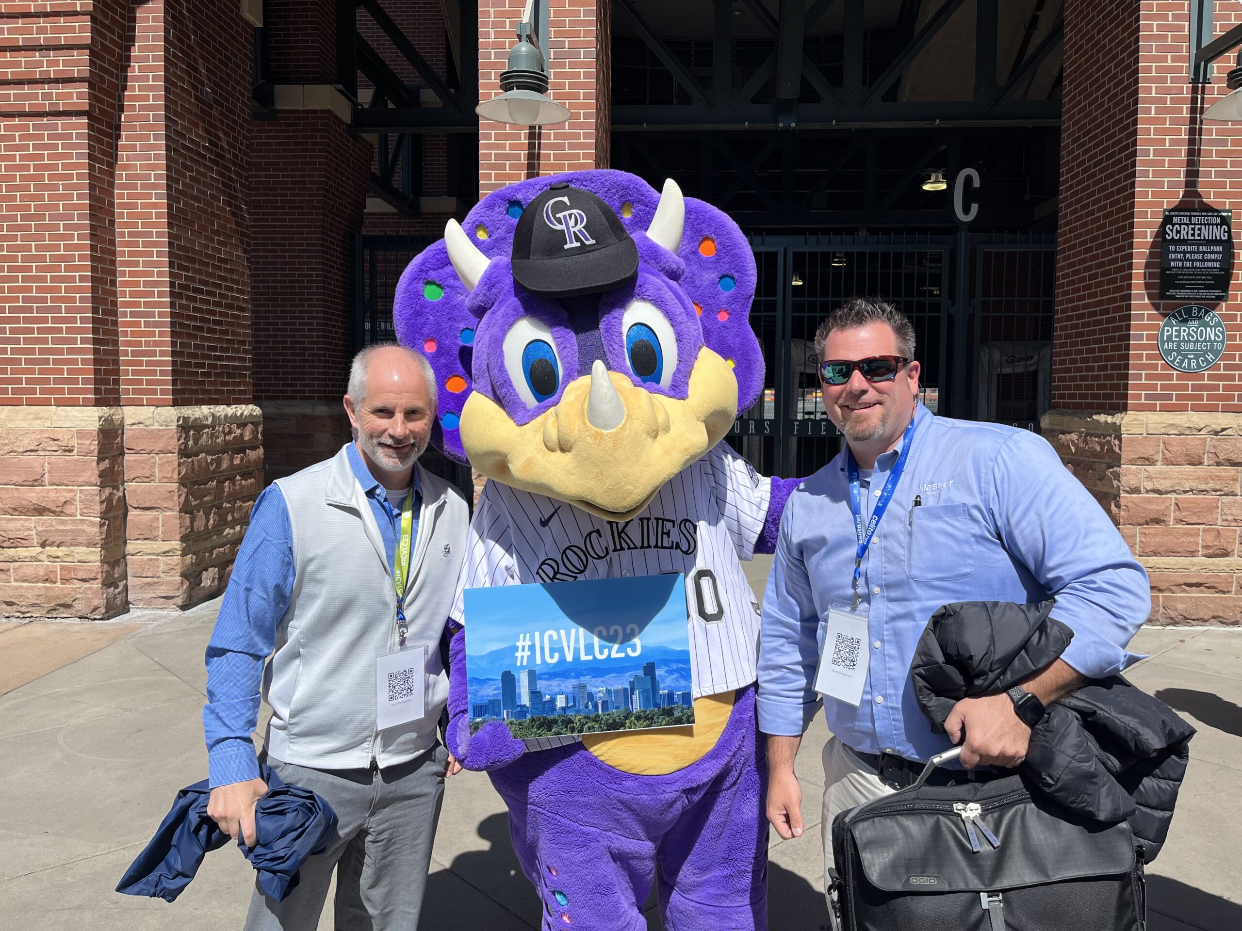 Two Messer Construction Company employees posing with the purple Colorado Rockies mascot