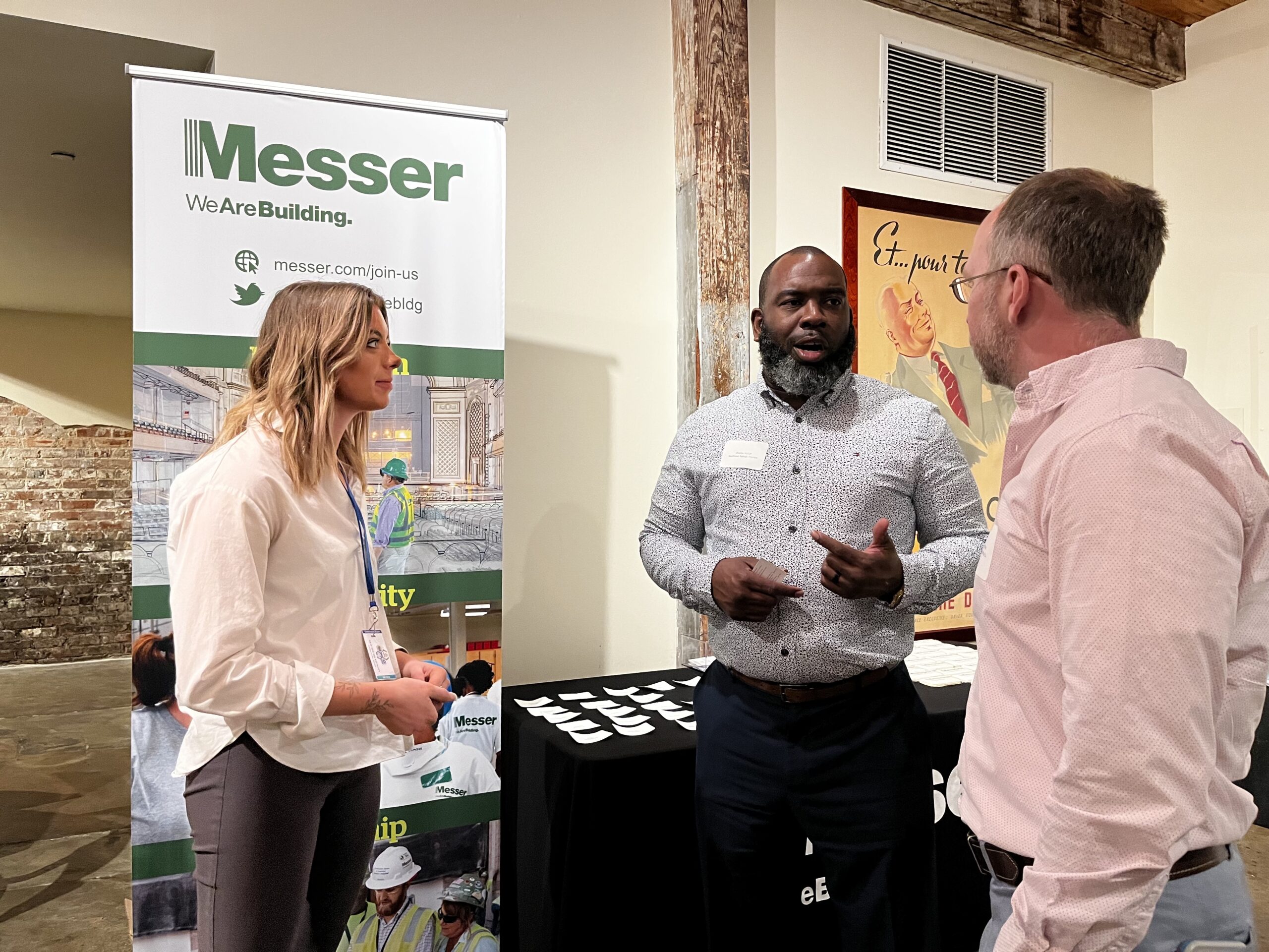 Two Messer Construction Company employees speaking with a business partner at an event.