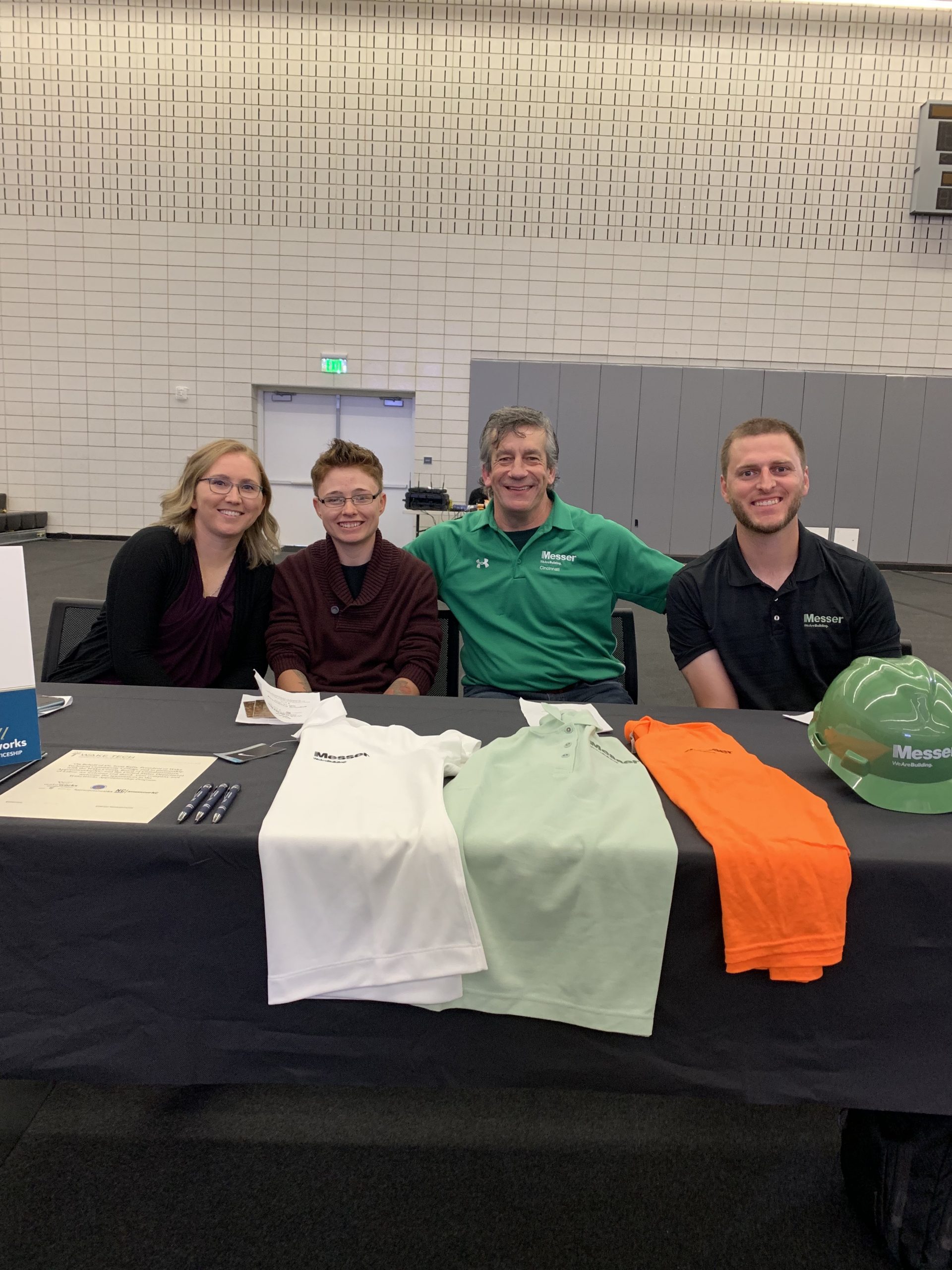 Four people sitting at a company booth at event