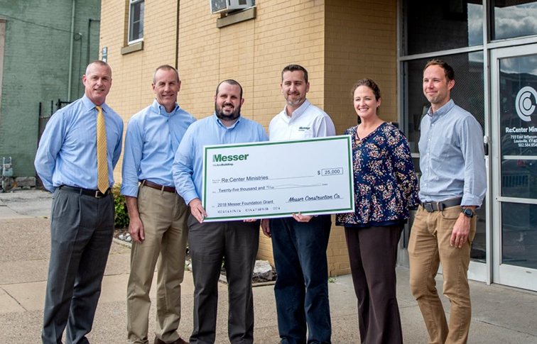 Group of people posing with large donation check