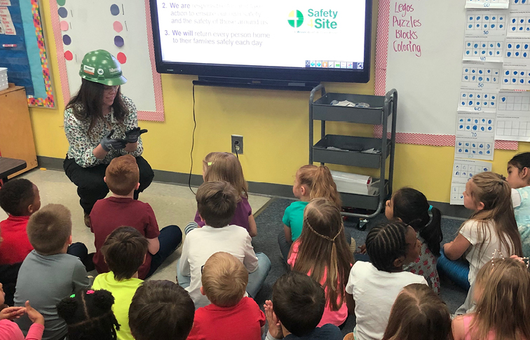 Children in classroom sitting on the floor and learning from a Messer project engineer about careers in construction